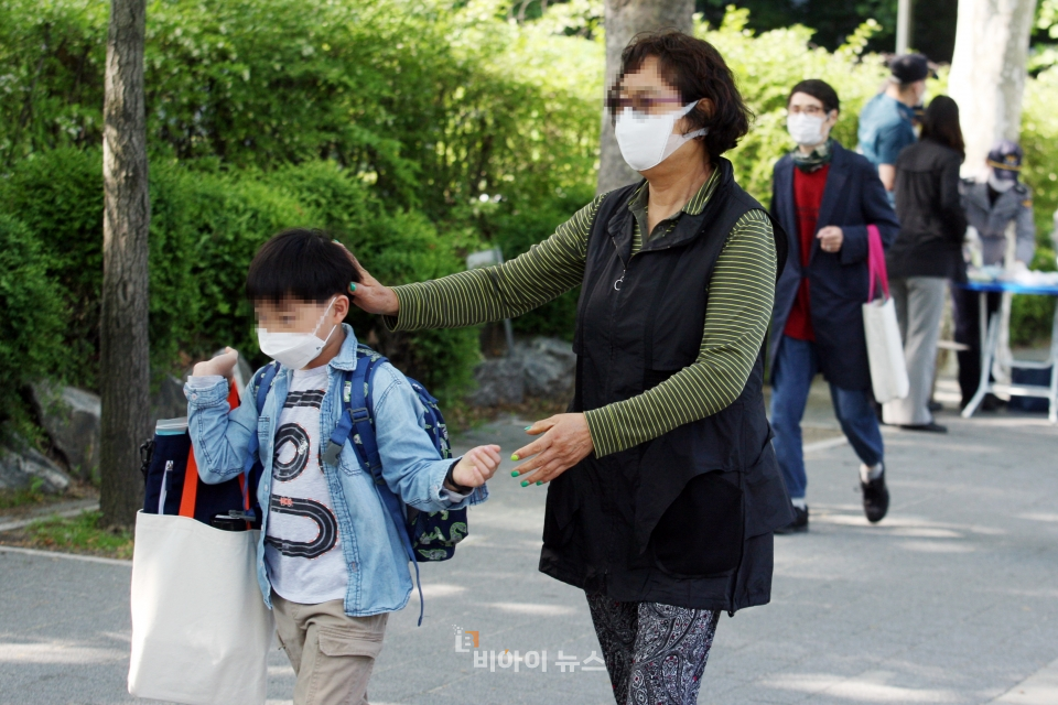 잘 다녀와. 할머니가 손자의 머리를 쓰다듬고 있다.
